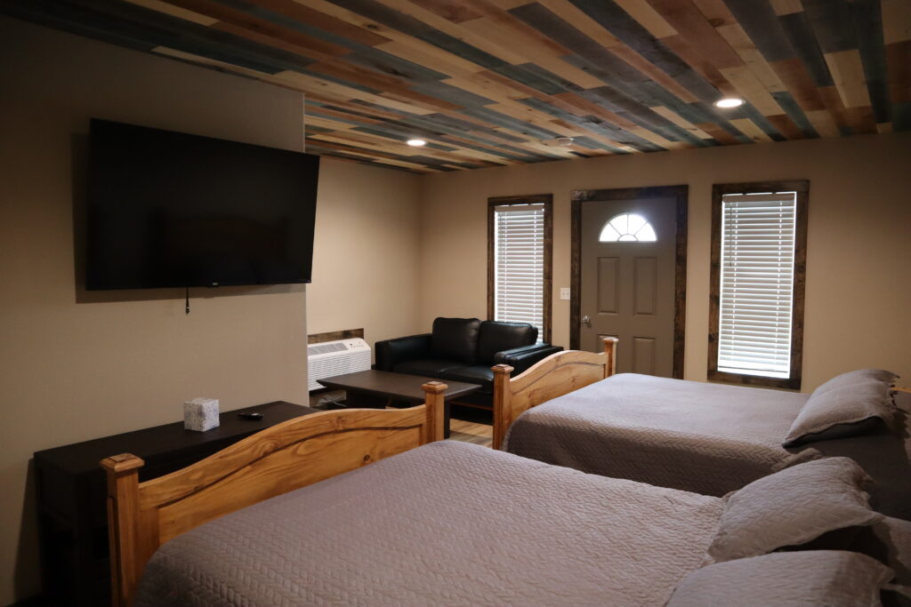 Bedroom in a Track One Lodging cabin with two queen beds and wall-mounted TV — Railyard 26, Oshkosh, Nebraska