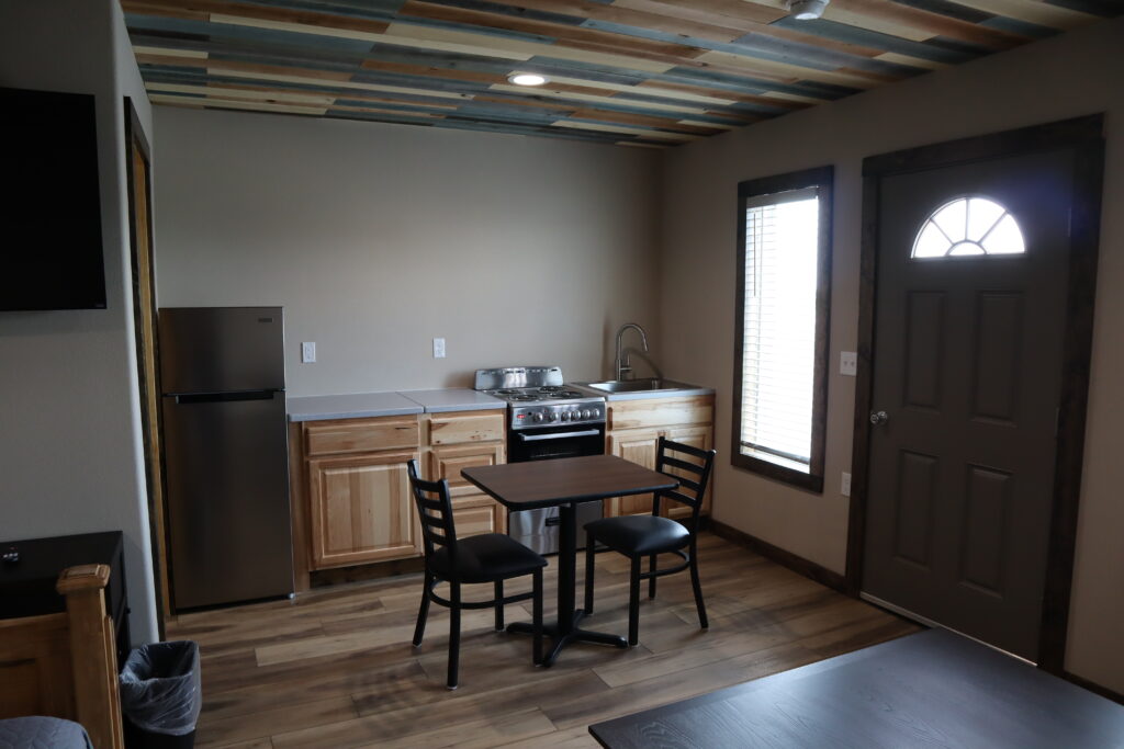 Full kitchen with stove, refrigerator, and dining table in a Track One Lodging cabin — Railyard 26, Oshkosh, Nebraska
